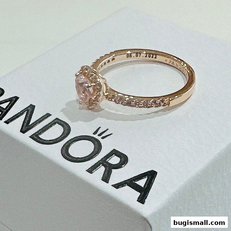 A rose gold ring with a pink stone and small diamonds on a Pandora box.