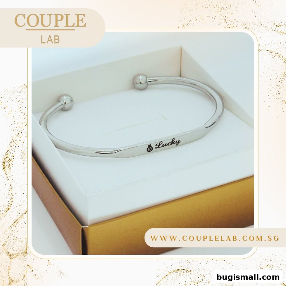 A silver bracelet with 'Lucky' engraved, presented in a gift box.