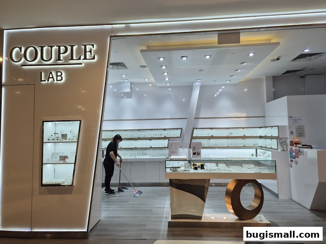 The entrance of Couple Lab jewelry store with display cases and a staff member cleaning.
