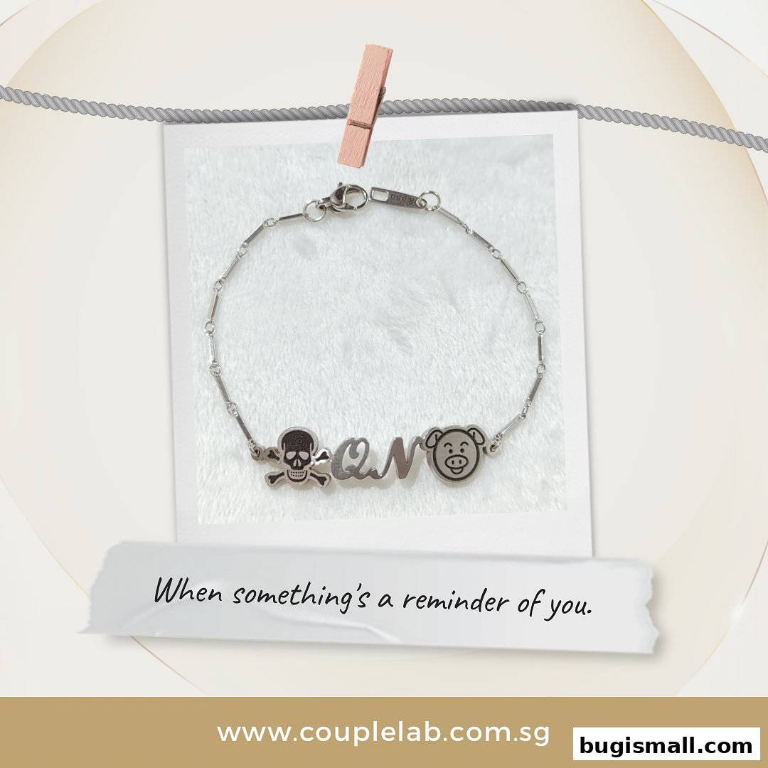 A silver bracelet with a skull, letters, and a pig charm, displayed with a quote.