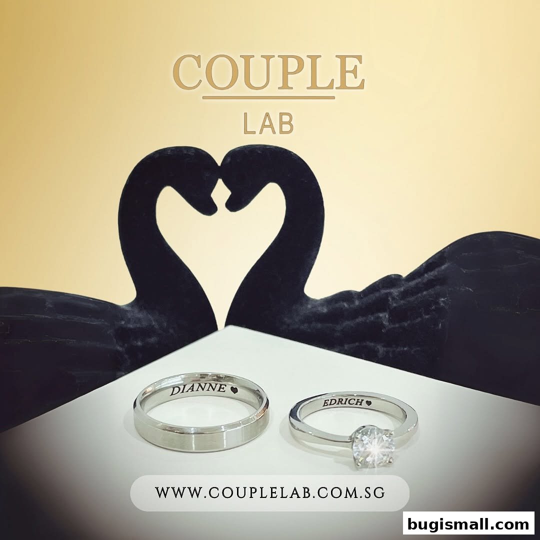 Two personalized wedding rings displayed with black swan sculptures forming a heart shape.