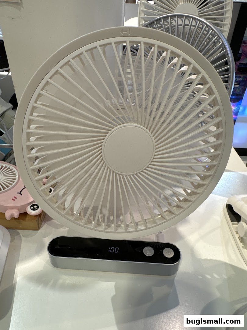 A close-up of a white portable fan with a digital display showing '100'.