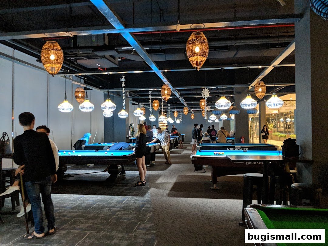 People playing pool in a dimly lit venue with decorative hanging lamps.