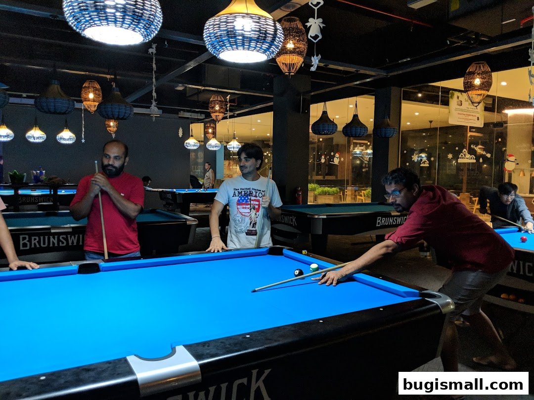 People playing billiards in a dimly lit entertainment venue with decorative lighting.