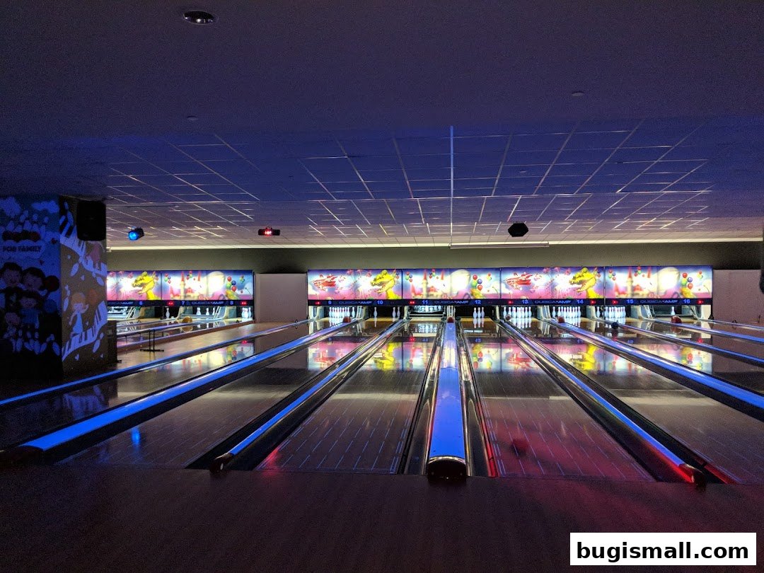 A bowling alley with multiple lanes illuminated by colorful lights and screens.