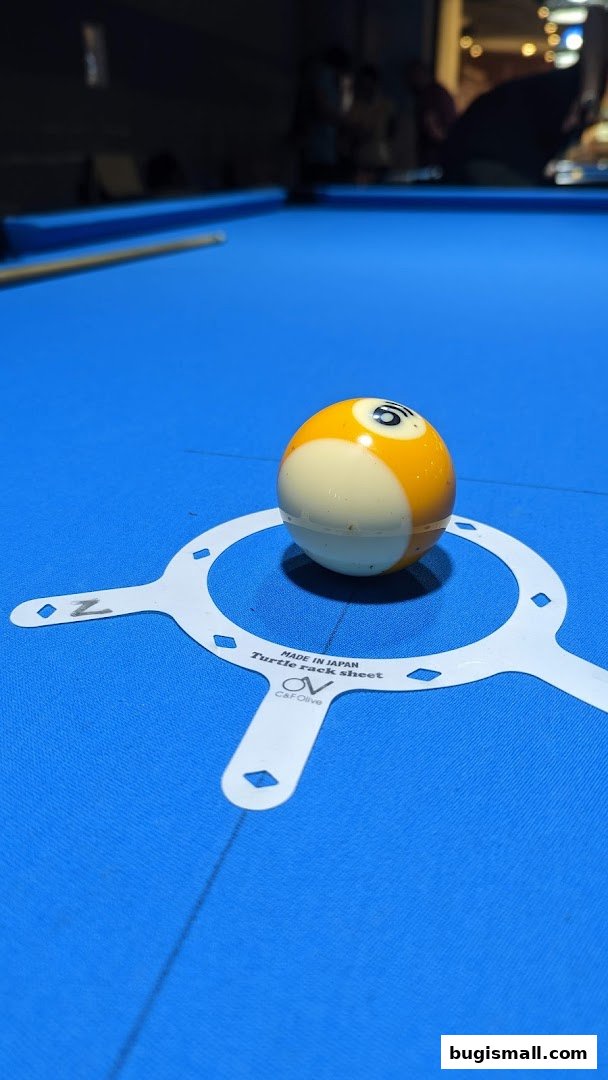 A billiard ball rests on a blue felt pool table with a rack sheet.