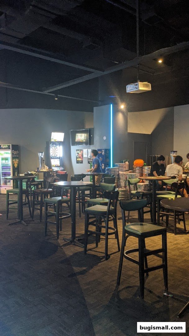 Interior of a bar with dart boards, high tables, and stools, with people seated.