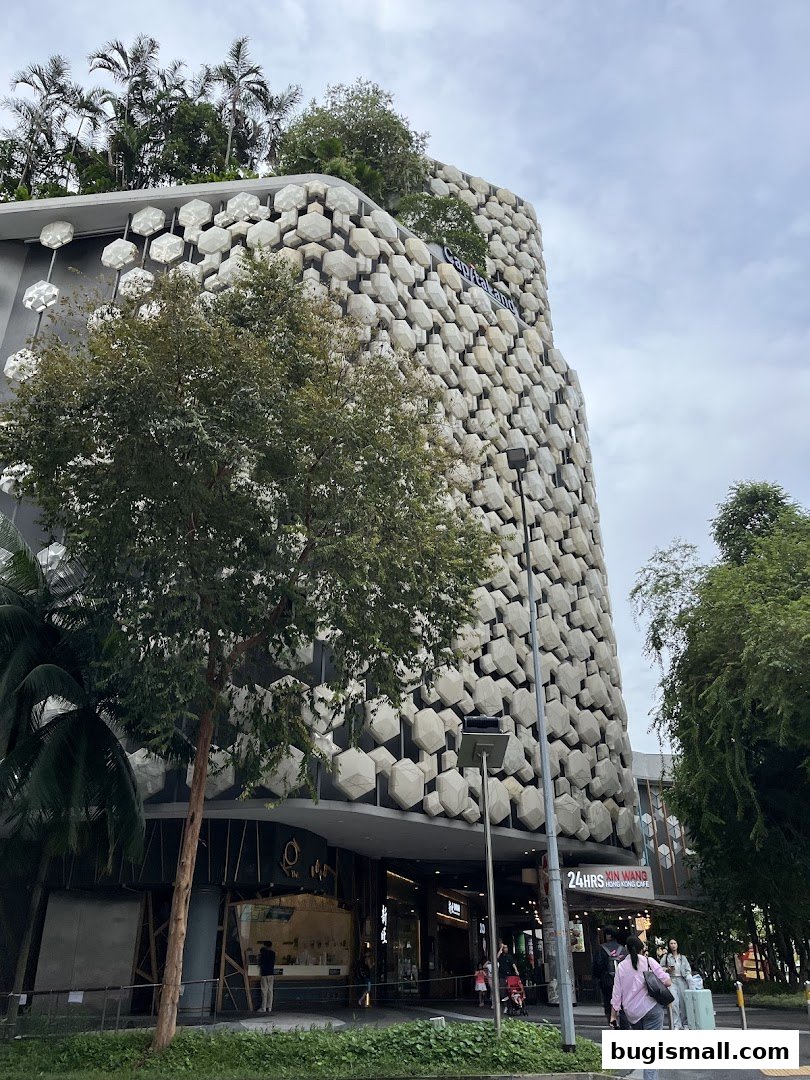 Exterior view of a modern building with a unique honeycomb facade and lush greenery.