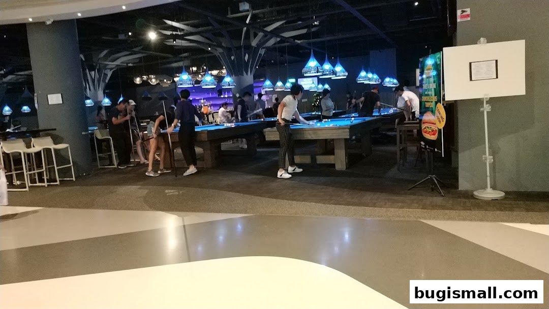 People playing billiards in a dimly lit venue with blue pendant lights.