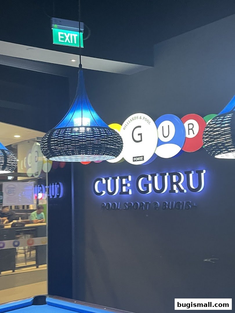 Interior shot of Cue Guru, a pool sports venue, with illuminated signage and a pool table.