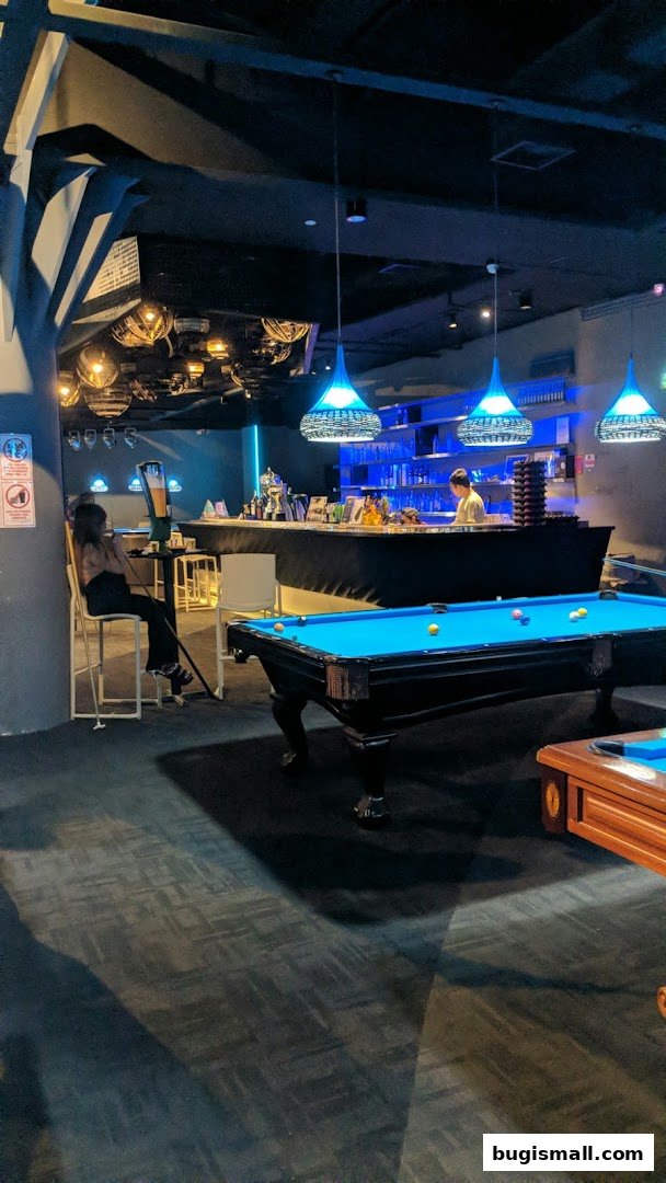Interior of a modern bar with pool tables, a bar counter, and ambient lighting.