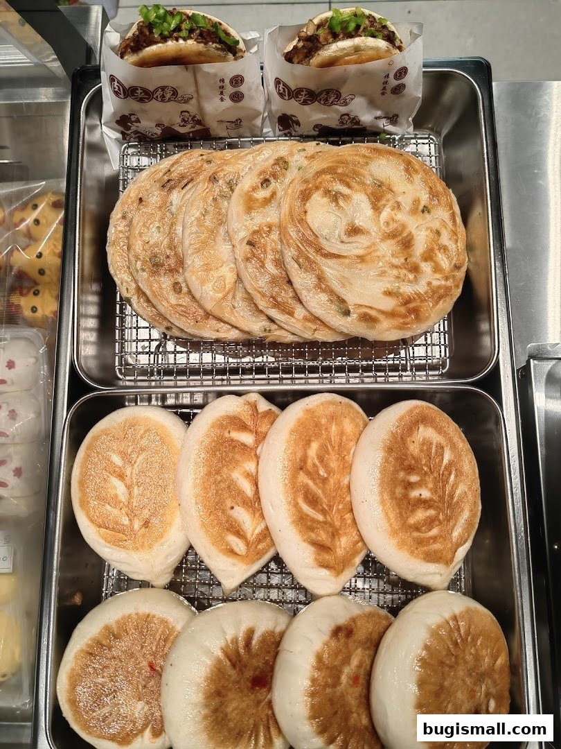 A display of freshly made Chinese pastries and buns, including scallion pancakes and filled buns.