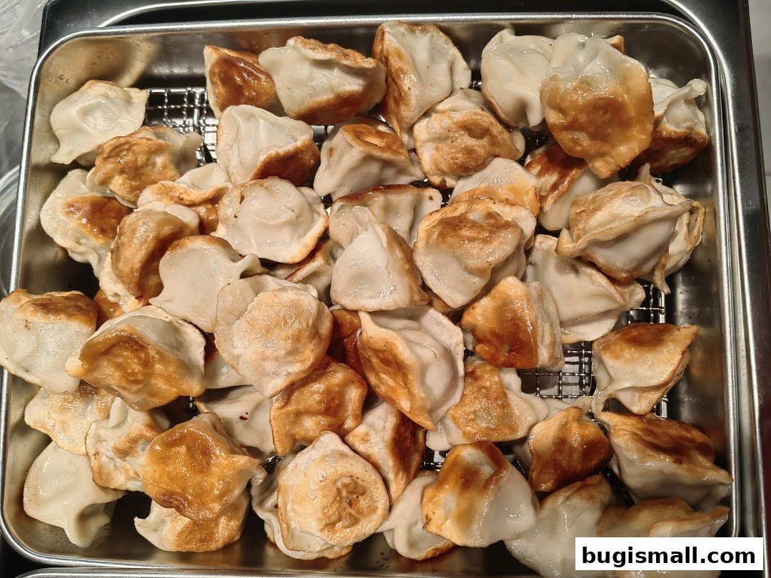 A close-up shot of a tray filled with freshly pan-fried dumplings.