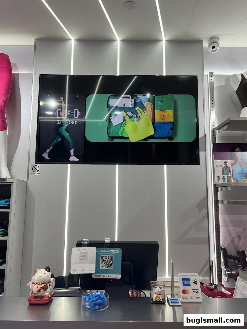 A retail store counter with a digital display showing activewear and luggage.