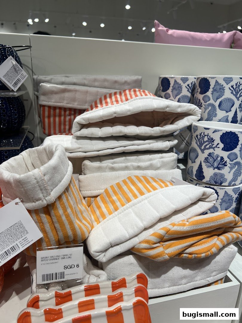 A display of fabric storage baskets with orange and white stripes and blue seashell-patterned pots.