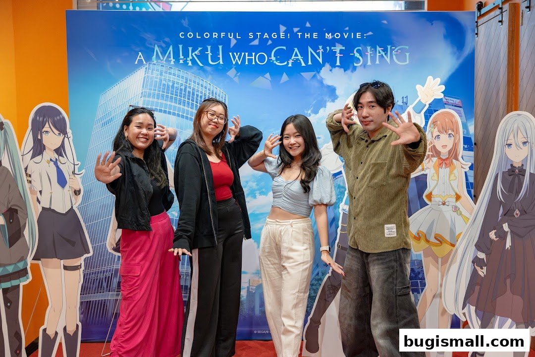 Four people pose with anime characters in front of a movie backdrop.
