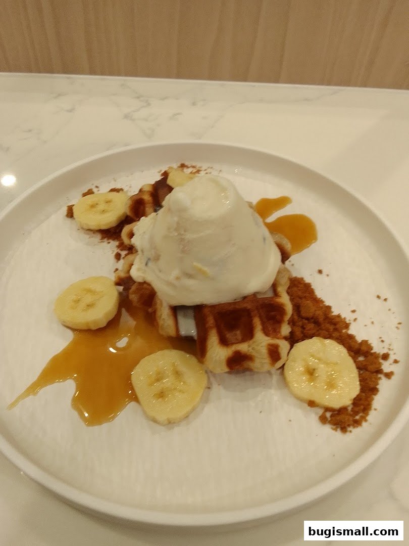 A delicious waffle dessert with ice cream, banana slices, and caramel sauce.