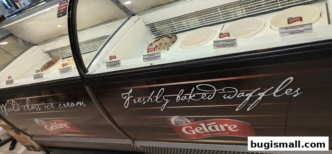 A display case filled with various flavors of ice cream and a sign advertising freshly baked waffles.