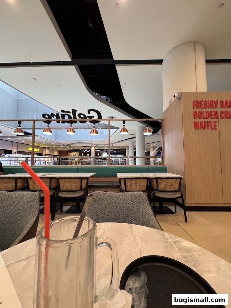 Interior view of Geláre Bugis with tables, chairs, and branding visible.