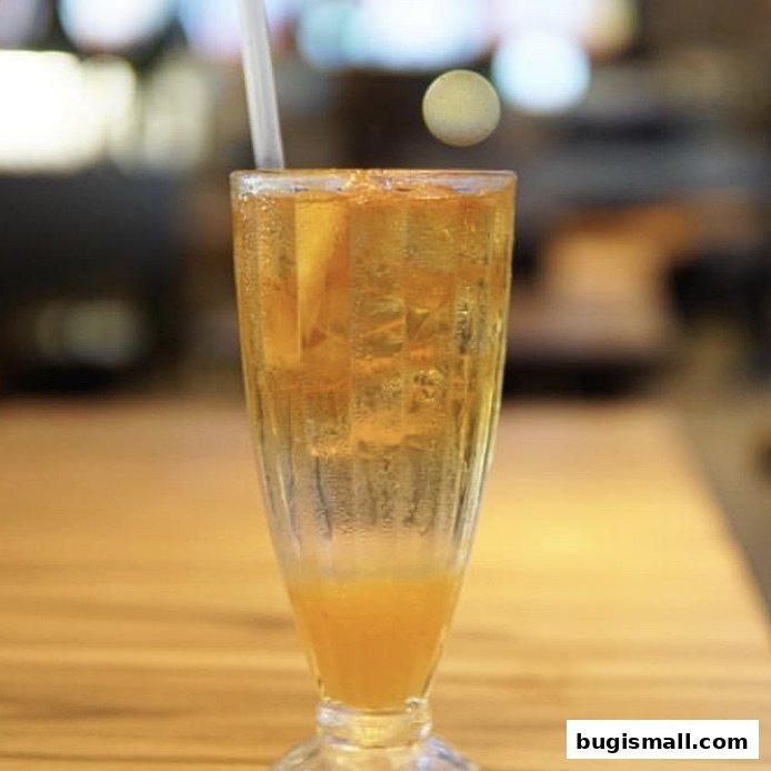 A tall glass filled with ice, a straw, and a refreshing orange-colored drink.