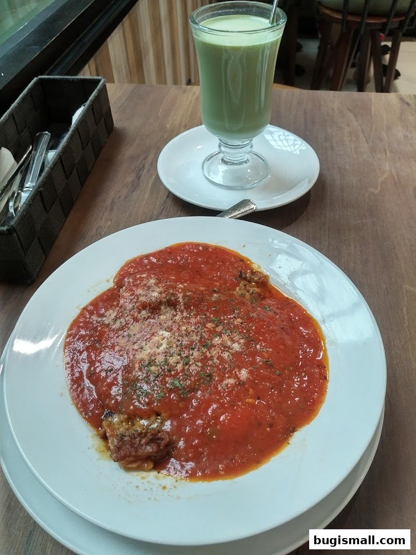 A plate of food with tomato sauce and a green drink on a wooden table.