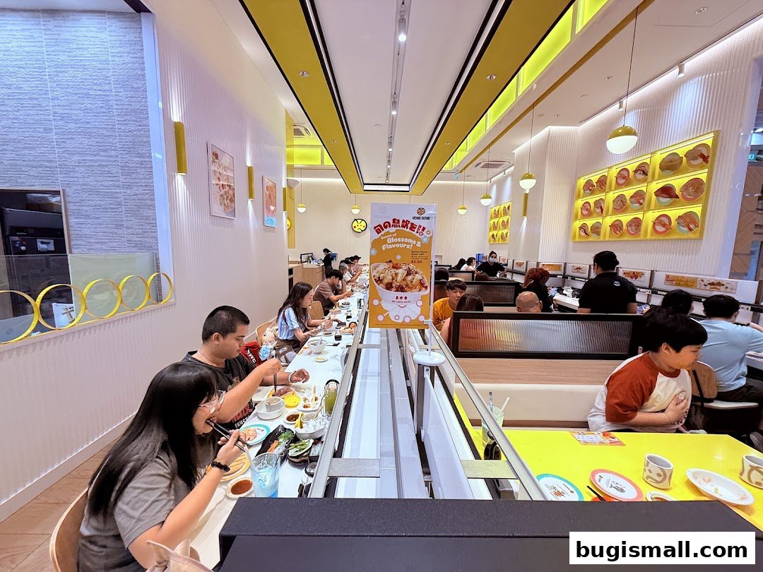 Diners enjoy sushi at a conveyor belt restaurant with bright yellow accents and sushi displays.