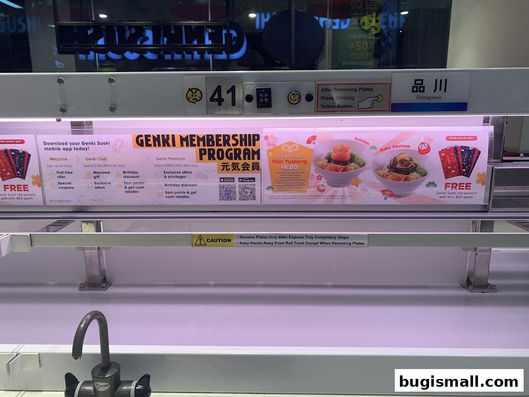 A conveyor belt sushi restaurant display with membership program information and food promotions.