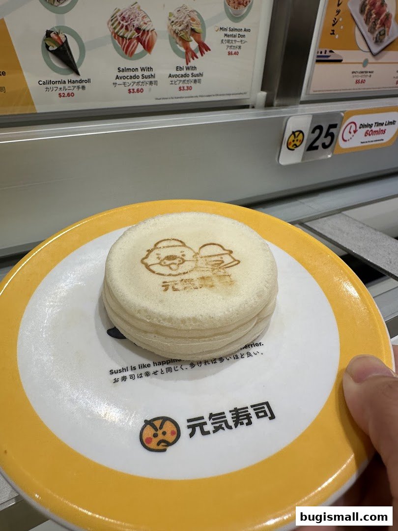 A plate of sushi with a cartoon character on a conveyor belt at Genki Sushi.