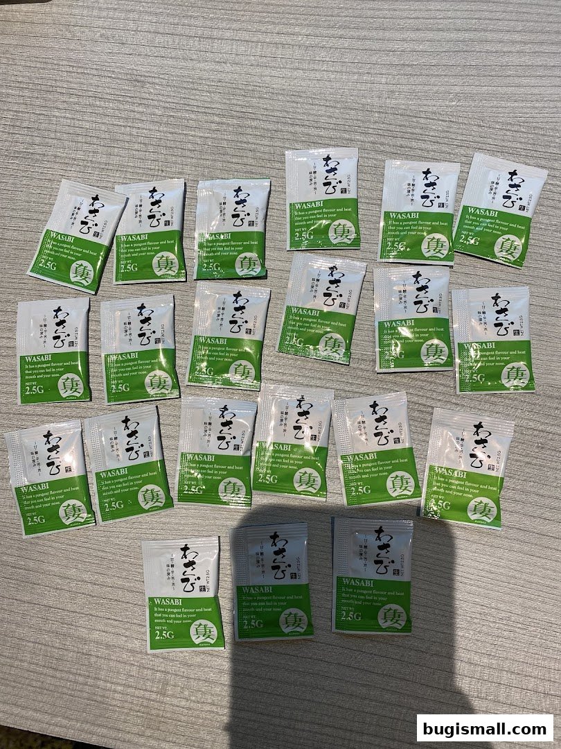 Multiple small packets of wasabi are neatly arranged on a wooden surface.