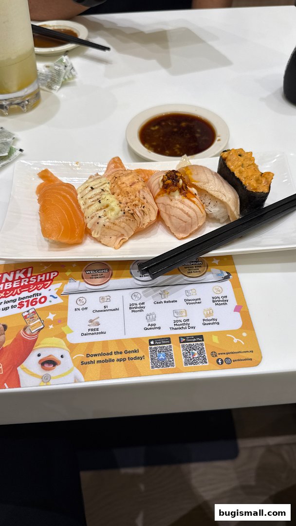 A plate of assorted sushi with chopsticks and a dipping sauce on a table.
