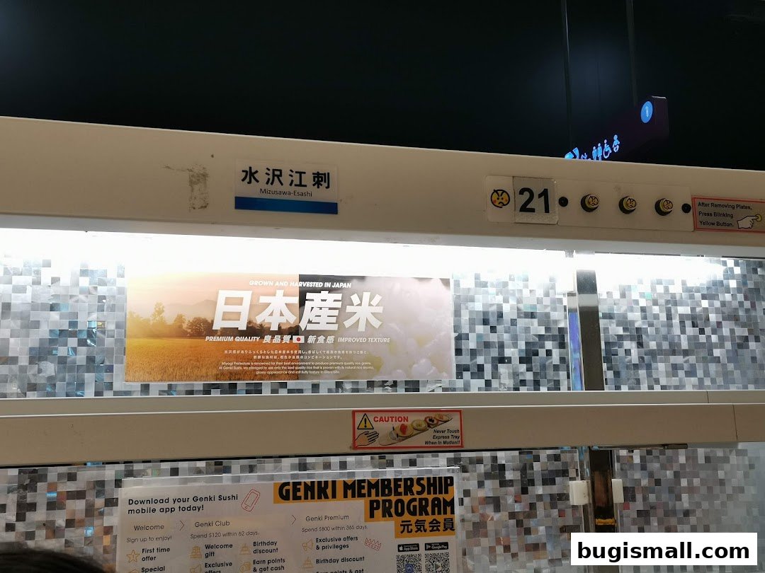 Interior view of Genki Sushi with a conveyor belt, advertising Japanese rice and a membership program.