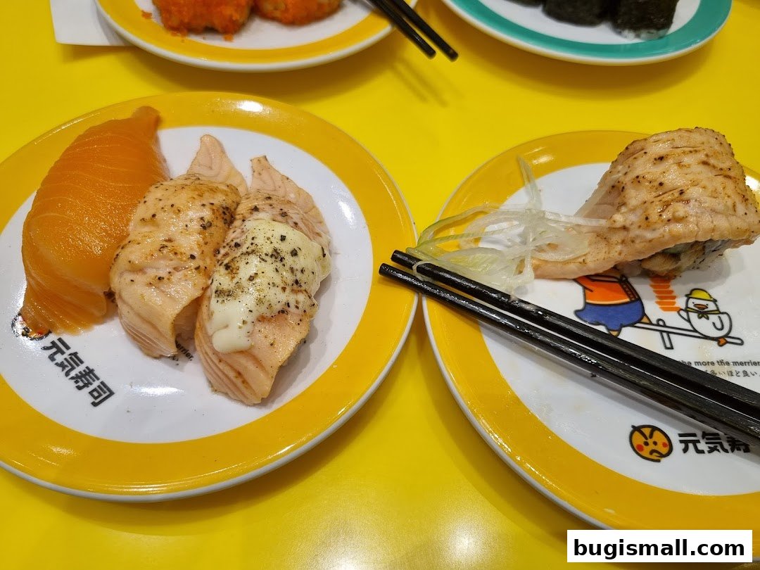 Plates of salmon sushi and other sushi dishes served on a yellow table.