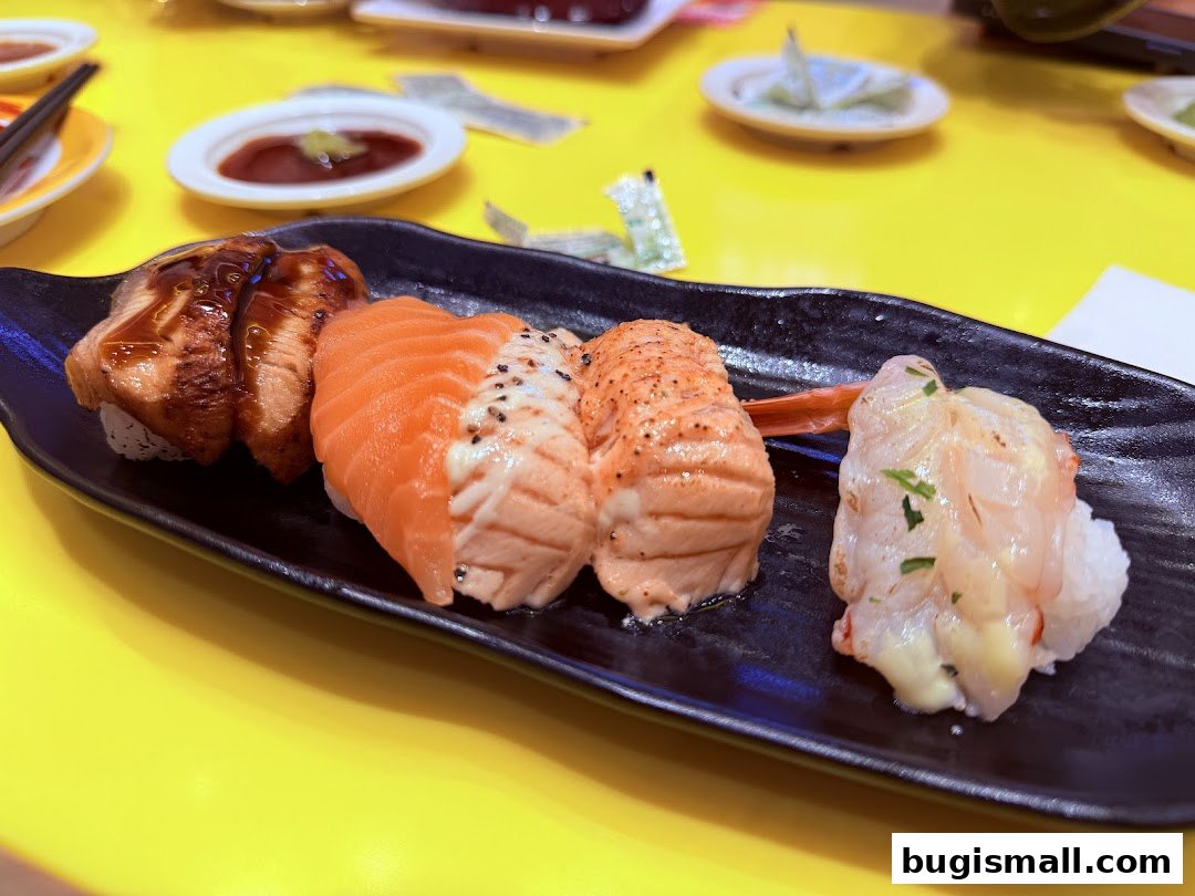 A close-up of a black plate filled with assorted sushi on a bright yellow table.