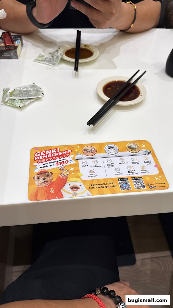 A table at Genki Sushi with chopsticks, soy sauce, and a membership promotion mat.