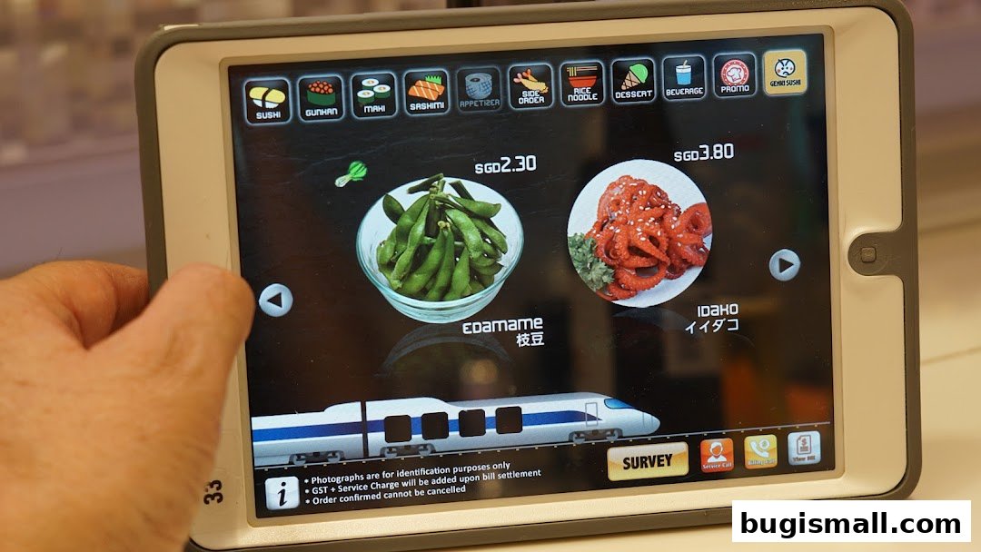 A tablet displays a digital menu for Genki Sushi, showing edamame and octopus dishes.