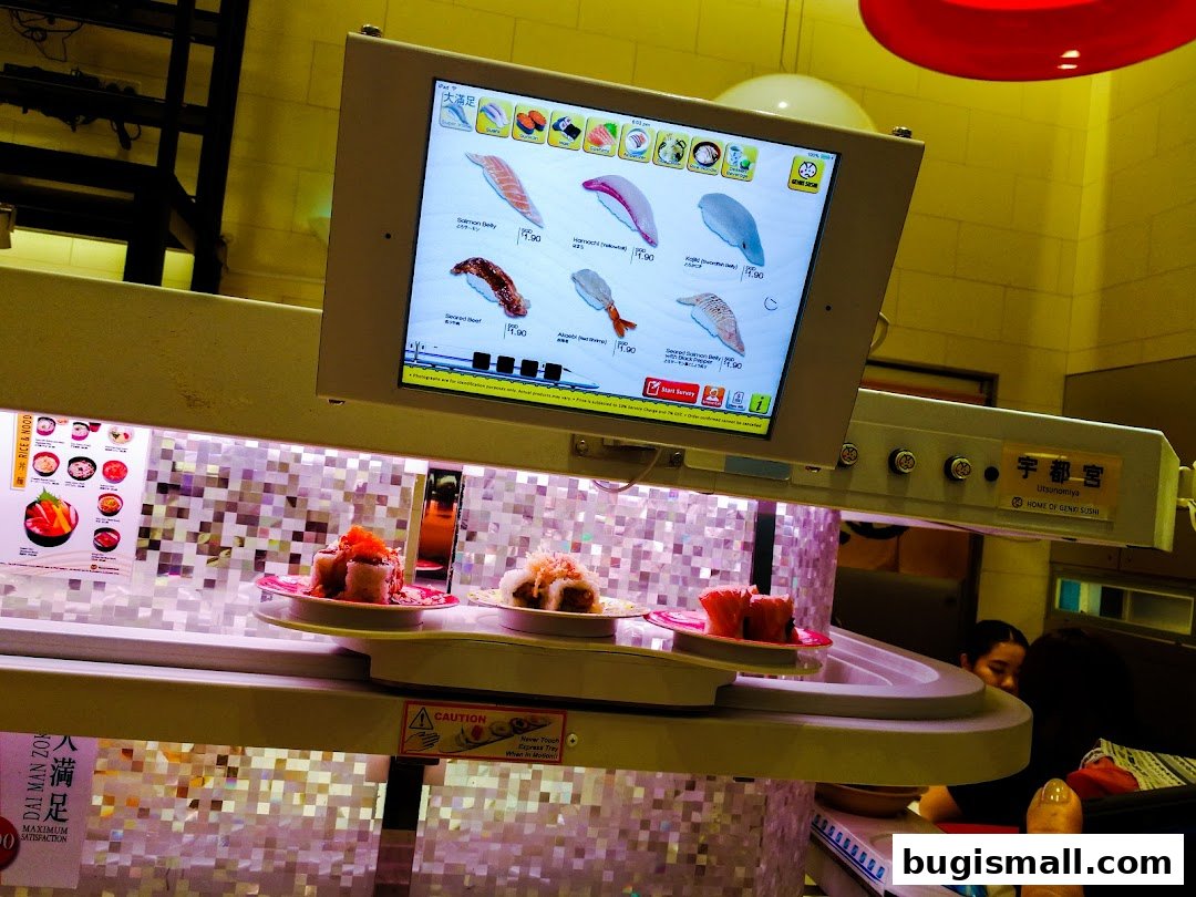 A conveyor belt sushi restaurant with a digital menu displaying various sushi items.