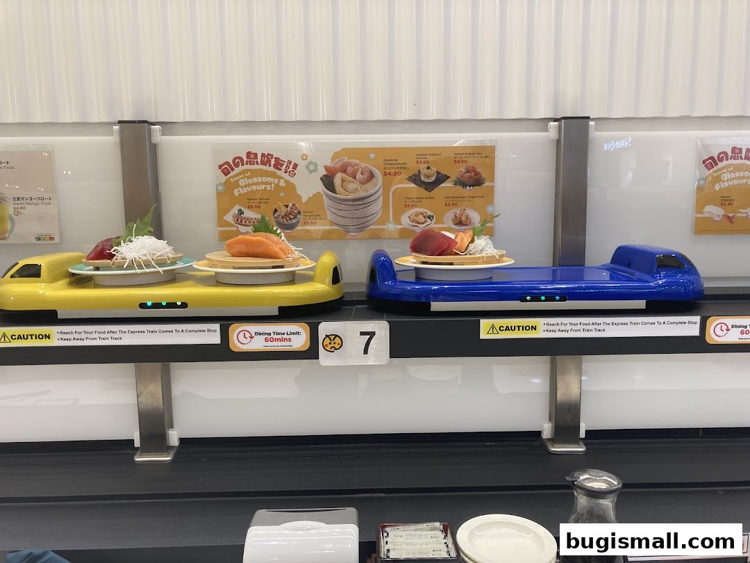Sushi served on conveyor belt trains, with menu boards in the background.
