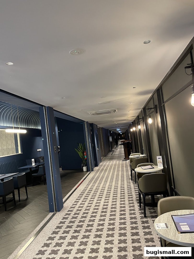 A long hallway with seating areas on both sides and patterned flooring.
