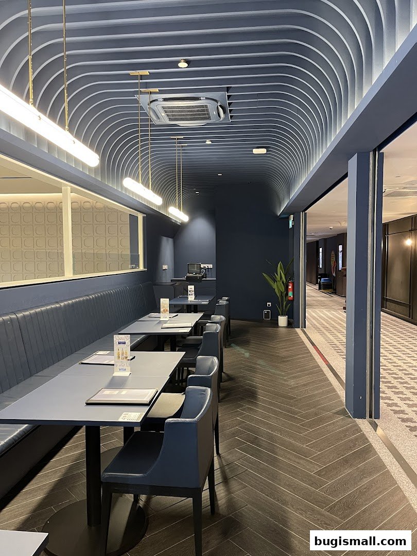 Interior view of a modern restaurant with blue seating, tables, and a distinctive arched ceiling.