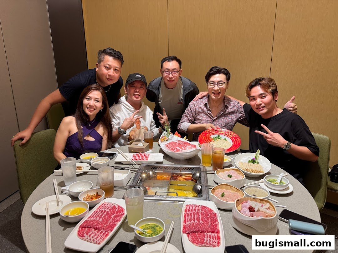 A group of six people enjoying a hot pot meal with various ingredients and dipping sauces.
