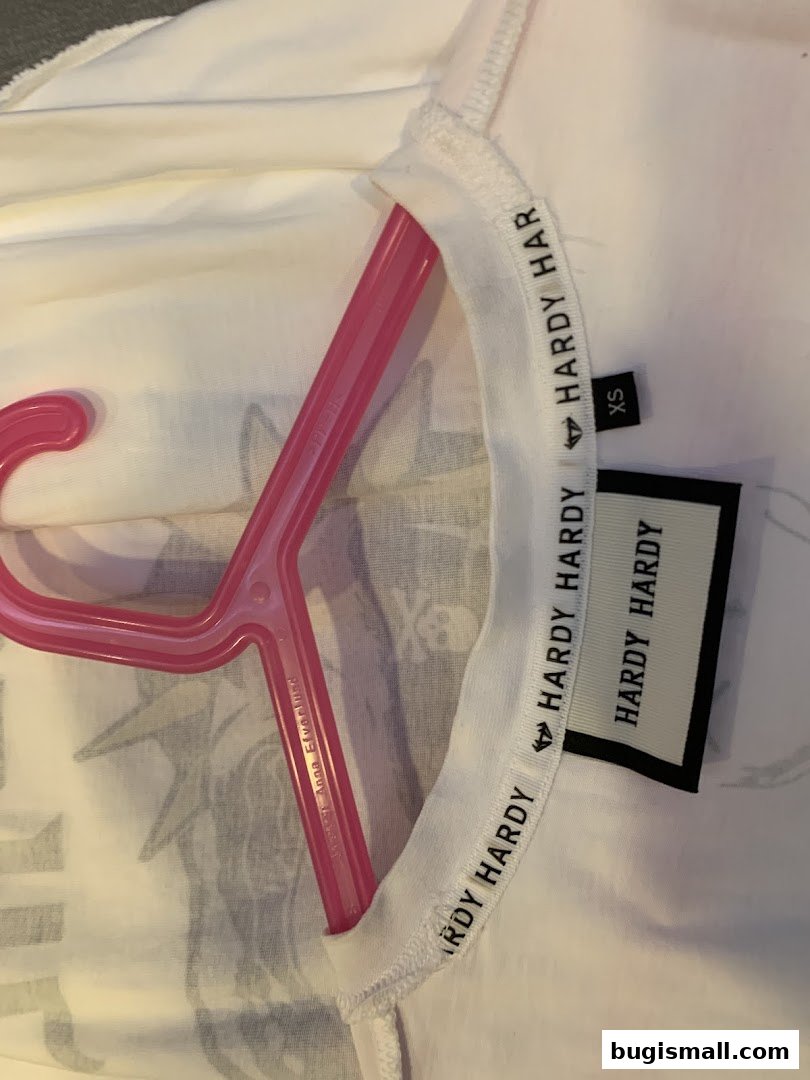 A white t-shirt with Hardy Hardy branding and an XS size tag on a pink hanger.