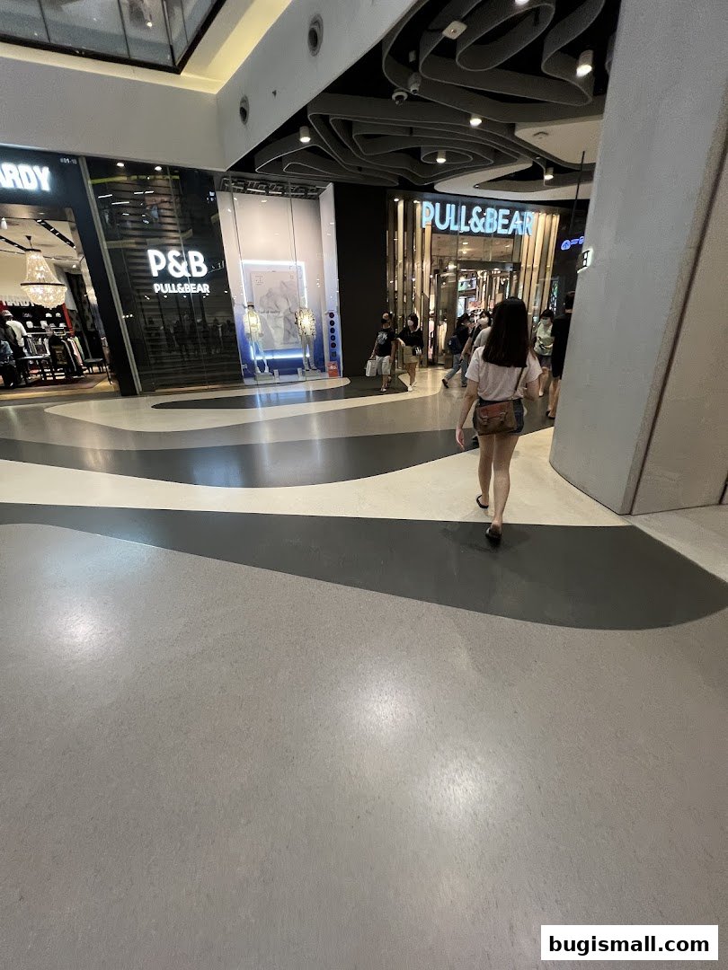 A woman walks past the entrances of fashion stores Hardy Hardy and Pull&Bear in a mall.