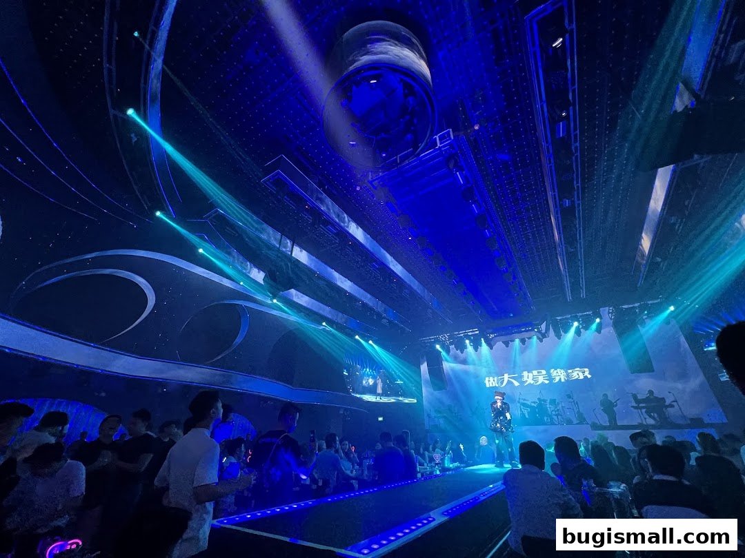 A lively karaoke venue with a stage performance and audience enjoying the show.