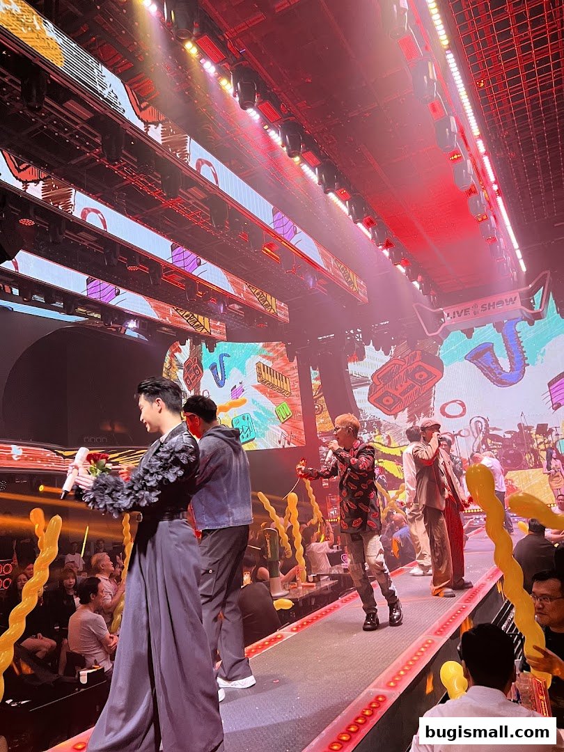 Performers on stage at a lively karaoke venue with audience members watching.