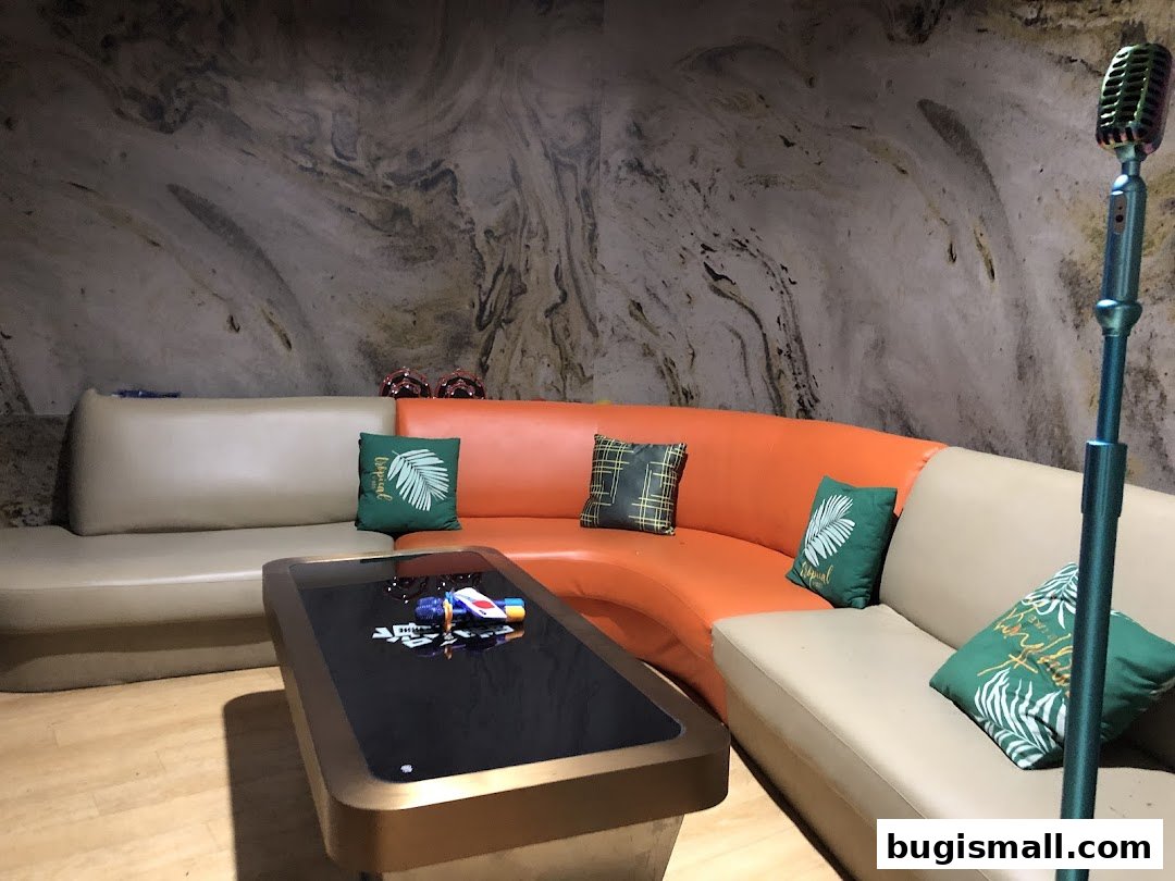 A modern karaoke room with comfortable seating, a touch-screen table, and a vintage microphone.