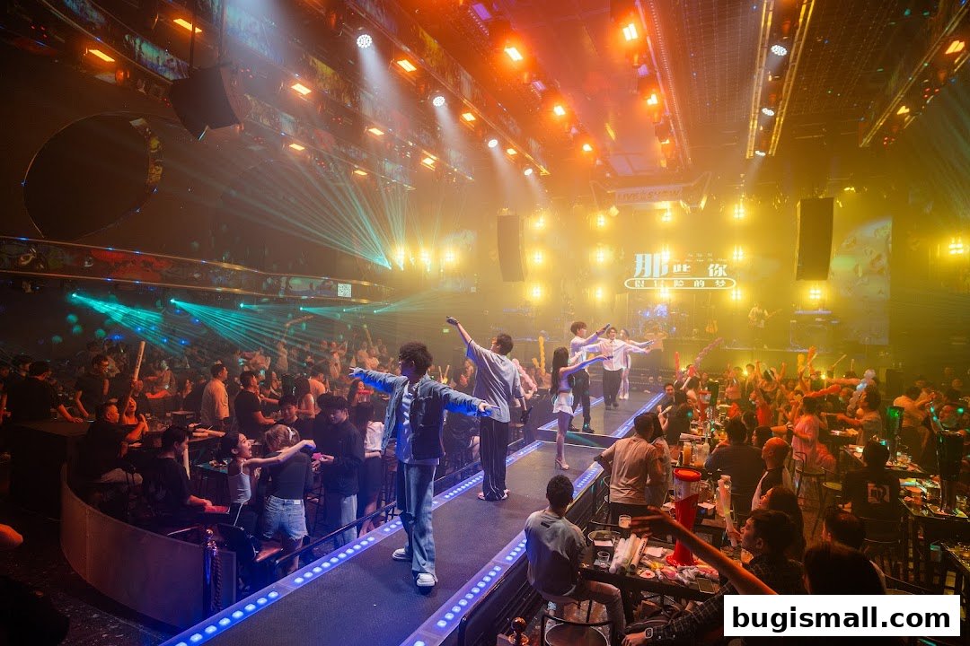 A lively indoor venue with a stage, performers, and a crowd enjoying a show with colorful lights.
