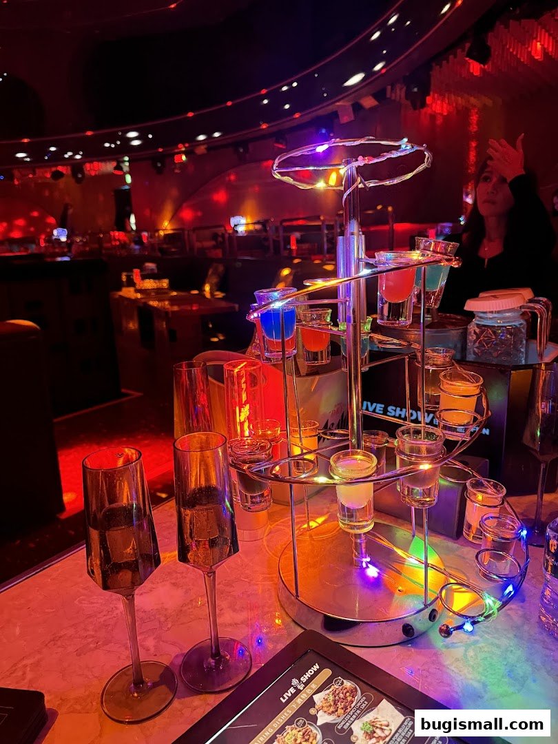 A shot tower with colorful drinks and champagne glasses on a table at a lively venue.