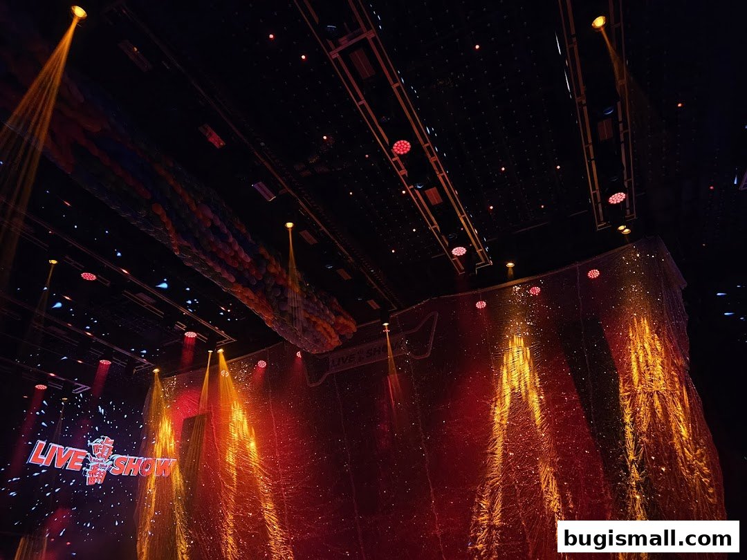 A stage with dramatic lighting, a shimmering backdrop, and a balloon installation.