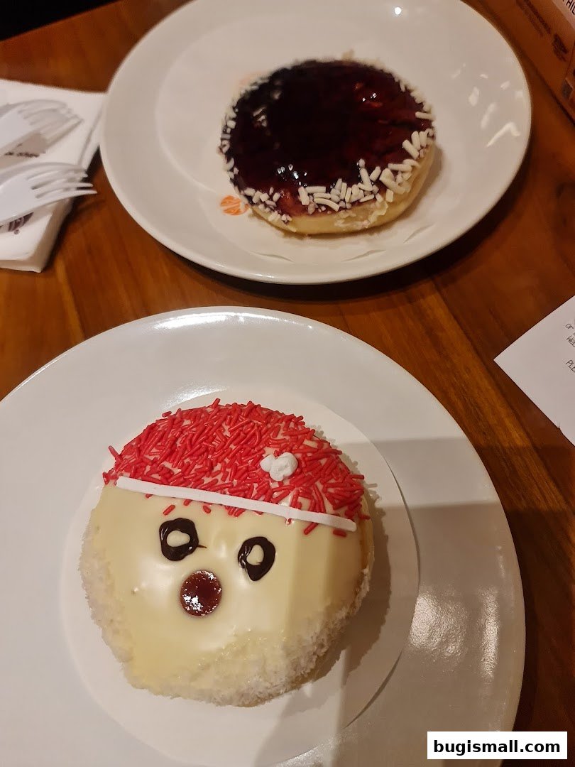 Two festive donuts, one resembling Santa Claus and the other topped with blueberry jam and sprinkles.