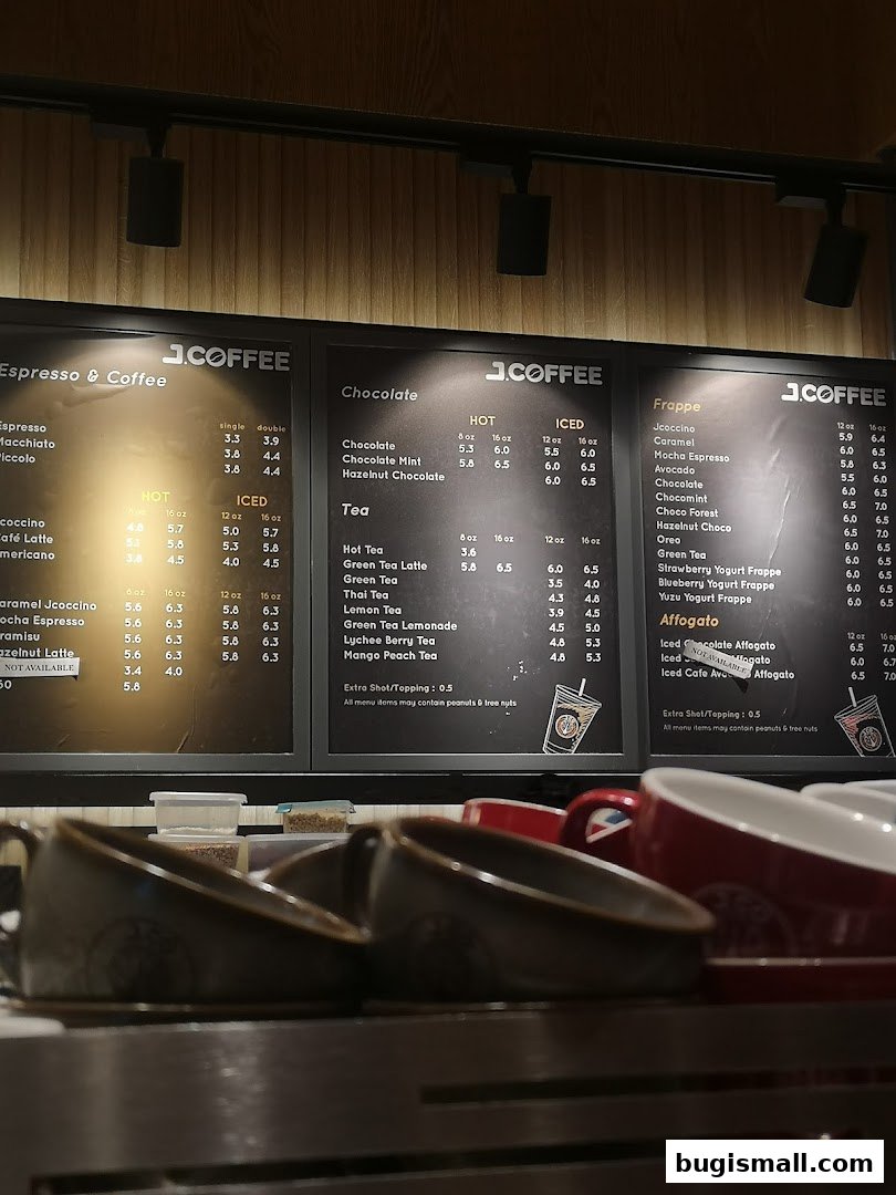 A menu board displaying various coffee, chocolate, tea, and frappe drinks with prices.